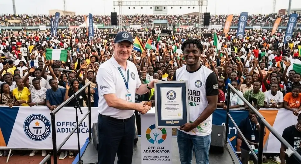 A GWR adjudicator presents an official certificate to a YESA representative in front of a stadium crowd